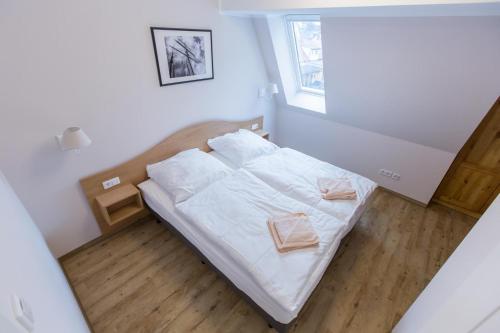 a bedroom with a bed with white sheets and a window at Sunnevelt-Apartment-18 in Kühlungsborn