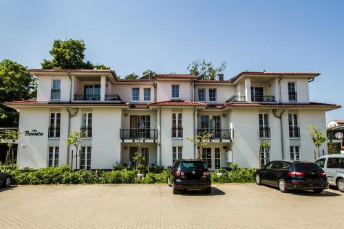 un grand bâtiment blanc avec des voitures garées devant lui dans l'établissement Villa-Borwin-Apartment-12, à Kühlungsborn