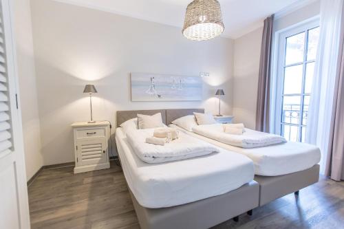 2 camas en una habitación con paredes y ventanas blancas en Villa-Borwin-Apartment-10, en Kühlungsborn