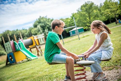 a boy and a girl sitting on a bench at a playground at Maison familiale in Moncoutant