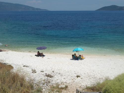 a group of people sitting on a beach with umbrellas at Villa Carina in Kounopetra