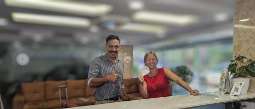 a man and a woman standing at a counter at Dreams Paradise Airport Residency in Nedumbassery