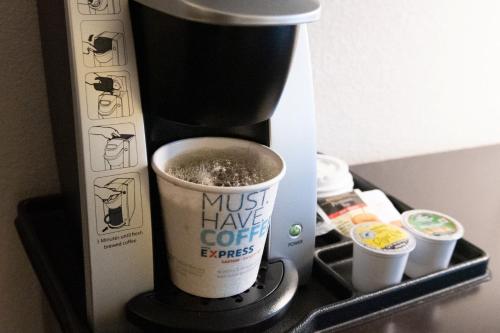 a coffee maker with a cup of coffee on a shelf at Holiday Inn Express & Suites Ironton by IHG in Ironton