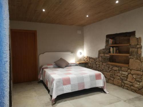 1 dormitorio con cama y pared de piedra en Country House El Permanyer en Olost