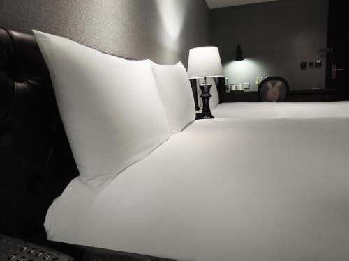 a bedroom with two beds with white pillows and a lamp at CHECK inn Taipei Main Station in Taipei