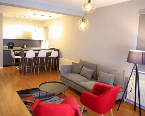 a living room with a couch and chairs and a kitchen at Parta Apartment in Pristina
