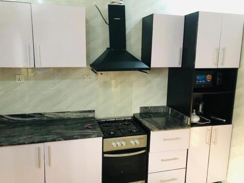 a kitchen with white cabinets and a black stove at Beautiful 4-Bedroom House in Ogombo