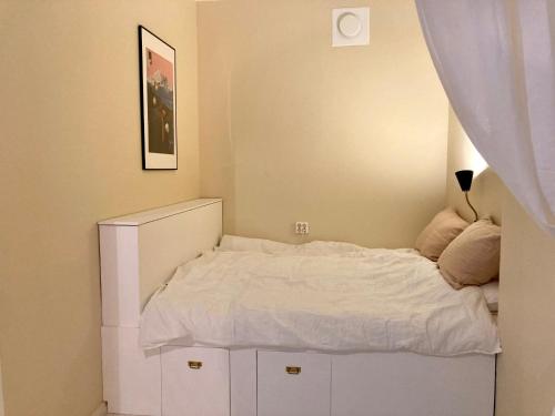 a small bedroom with a white bed and a curtain at Spacious (44 sqm) bohemian studio in trendy Kallio in Helsinki