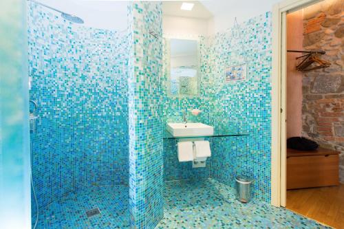 a blue tiled bathroom with a sink and a shower at Grand Hotel Entourage - Palazzo Strassoldo in Gorizia