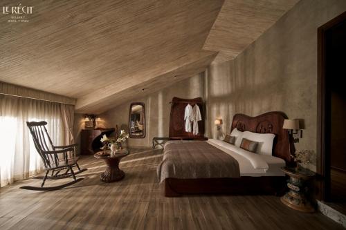 a bedroom with a large bed and a chair at Le Récit Boutique Hôtel de Dalat in Da Lat