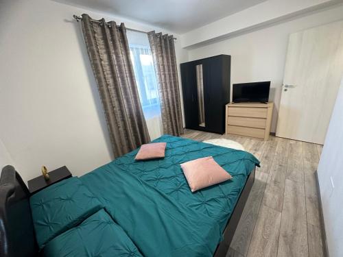 - une chambre avec un lit vert et une télévision dans l'établissement Apartament Elena, à Bragadiru