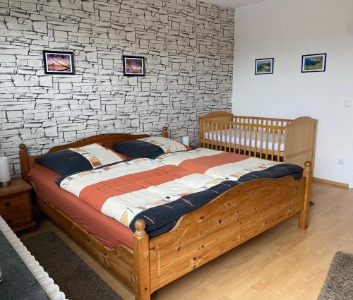 1 dormitorio con cama de madera y pared de ladrillo en Ferienwohnung Maifeldtraum, en Mertloch