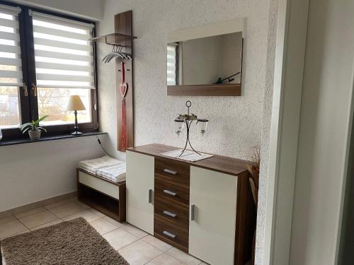 a bathroom with a vanity with a mirror and a window at Ferienwohnung Maifeldtraum in Mertloch