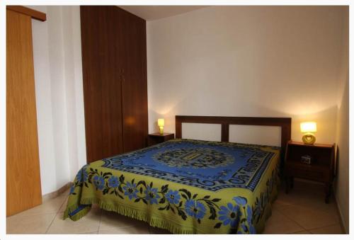 a bedroom with a bed with a blue and yellow blanket at Villette Ninfee in Marina di Mancaversa