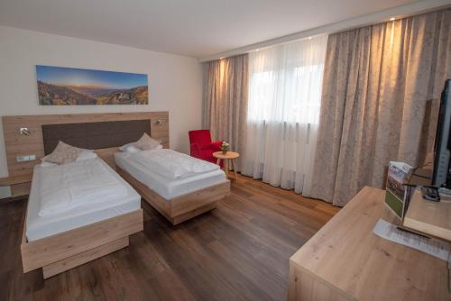 a hotel room with two beds and a television at Gasthof Pfauen in Oberkirch