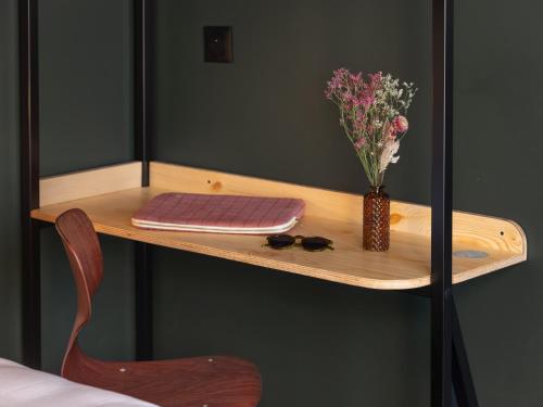 a wooden table with a vase of flowers on it at Eklo Lyon in Vénissieux