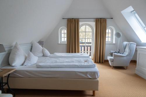 a bedroom with a bed and a chair and a window at Hotel Alster Au in Duvenstedt