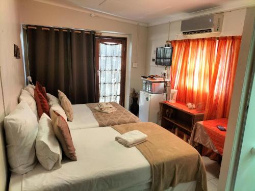 a hotel room with two beds and a desk at Garden Cottage Guest House in De Aar