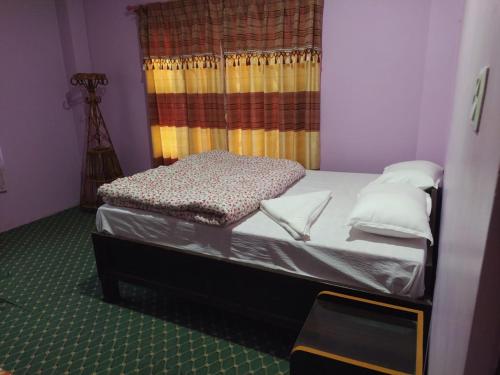 a small bed in a room with a window at Hotel Sauraha Gaida House in Chitwan