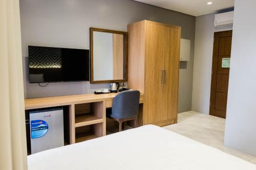 a bedroom with a desk with a tv and a mirror at The Manaoag Hotel in Manaoag