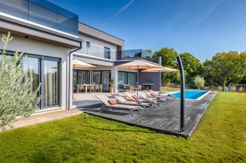a backyard with a deck with chairs and a pool at Villa Borealis in Raša
