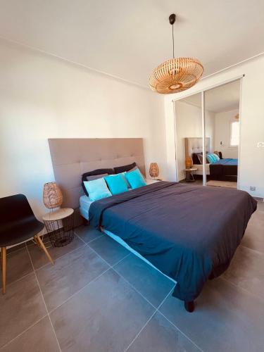 - une chambre avec un grand lit bleu et un lustre dans l'établissement Cannes CROISETTE - plages - palais - bord de mer - Appartement moderne et lumineux avec balcon, à Cannes