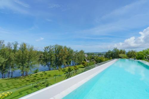 an infinity pool with a view of the water and trees at Skypark Apartments by Laguna Phuket in Bang Tao Beach