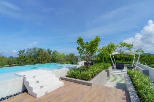 an outdoor swimming pool with a wooden deck and a patio at Skypark Apartments by Laguna Phuket in Bang Tao Beach