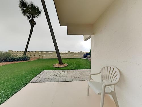 a white chair sitting on a porch with a palm tree at Aqua Villa #101 in Fort Walton Beach