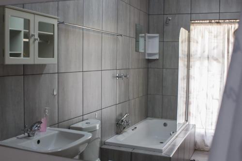 a bathroom with a sink and a tub and a toilet at Gemstone Guest House in Klerksdorp