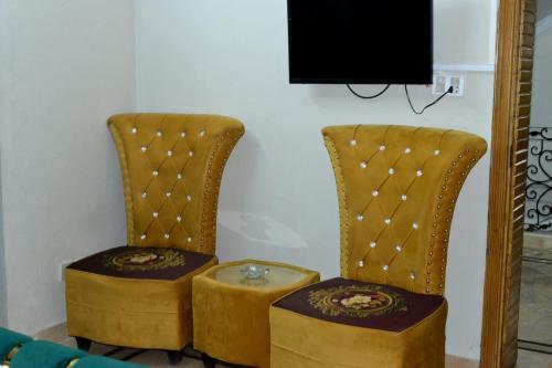 a pair of chairs with a table and a tv at Galaxy Lodge in Islamabad