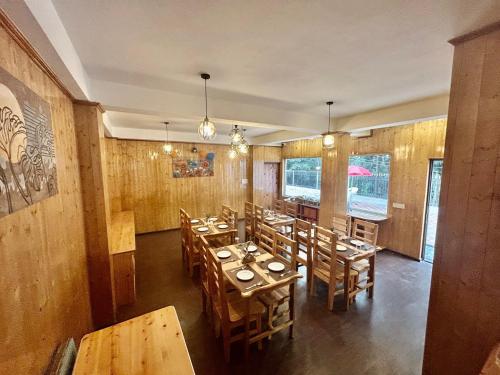 uma sala de jantar com mesas e cadeiras de madeira em Amaira Resort & Farms - Mirik, West Bengal em Mirik