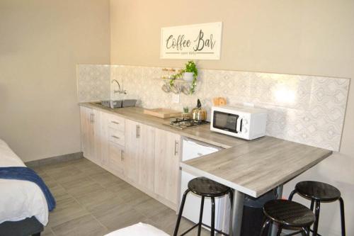 a kitchen with a counter with a microwave and a bed at Bethlehem Sundowners Guesthouse in Bethlehem