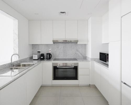 a white kitchen with white cabinets and a sink at Luxury 2 bedroom apartment in Madinat Jumeirah Living in Dubai