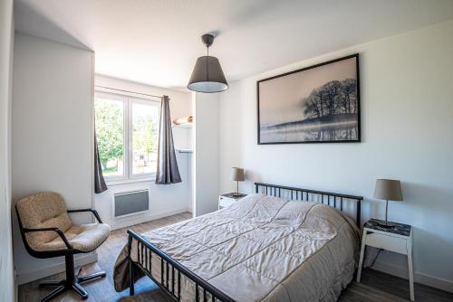 a bedroom with a bed and a chair and a window at Gîte Martin pêcheur au coeur de la nature in Moncoutant