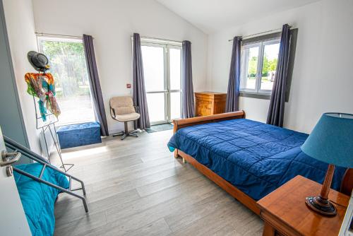 a bedroom with a blue bed in a room with windows at Gîte Libellule au coeur de la nature in Moncoutant