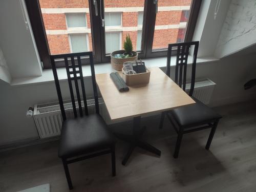 a table and two chairs in a room with a window at Het Kapittel in Ieper