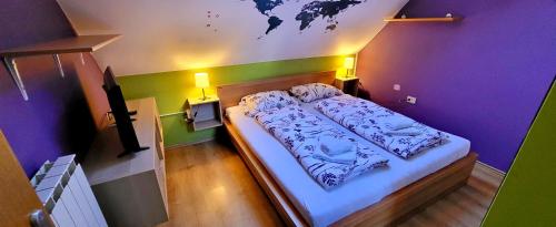 a bed in a room with purple and green walls at Simonai Apartment in Bovec