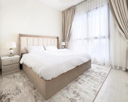 a white bedroom with a large bed and a window at Luxury 2 bedroom apartment in Madinat Jumeirah Living in Dubai