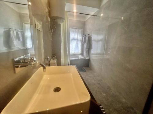 a white bathroom with a sink and a shower at Amaira Resort & Farms - Mirik, West Bengal in Mirik