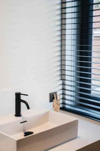 lavabo blanco en un baño con ventana en Vakantiewoning number 44, en Ypres