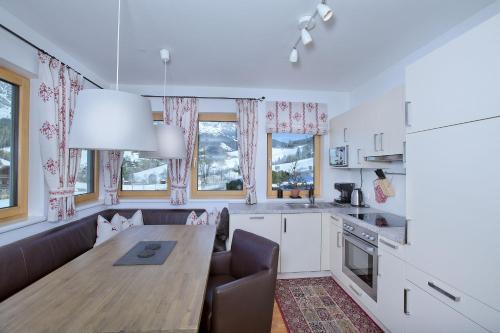 a kitchen with a wooden table and a dining room at Ski In-Ski Out -Superior 2 Bedroom with Sauna at Mountain Resort Dienten am Hochkönig in Dienten am Hochkönig
