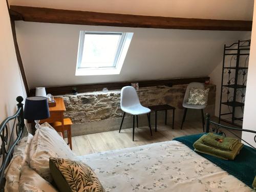Schlafzimmer mit einem Bett, einem Schreibtisch und einem Fenster in der Unterkunft Ferme de Noyes in Sourdeval