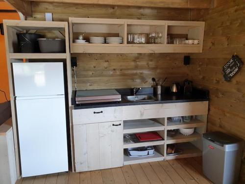 een keuken met een aanrecht en een witte koelkast bij Safaritent Betuwe Lodge in Kesteren