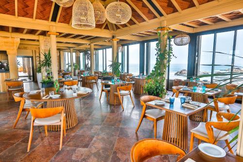 a restaurant with tables and chairs and windows at Riad Mimouna in Essaouira