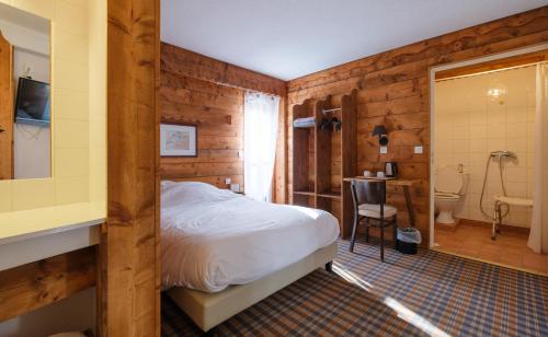 a bedroom with wooden walls and a bed and a bathroom at Cit'Hotel Le Montreal in Chalons en Champagne