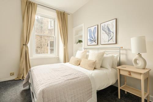 a white bedroom with a bed and a window at The Raeburn Residence - Stockbridge in Edinburgh