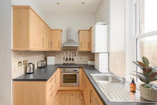 een keuken met houten kasten en een wastafel bij The Raeburn Residence - Stockbridge in Edinburgh