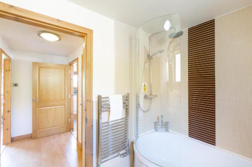 La salle de bains est pourvue d'une baignoire et d'une douche en verre. dans l'établissement Douglas Fir Lodge with Hot tub, à Cupar