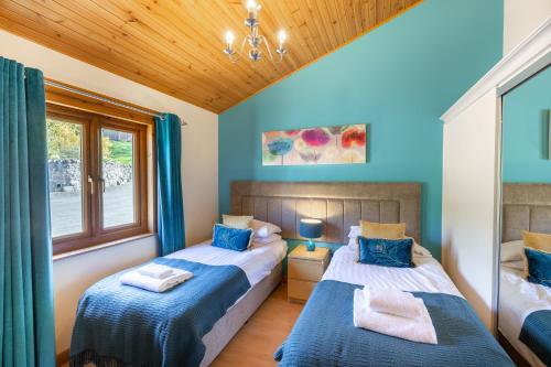 two beds in a room with blue walls and wooden ceilings at Douglas Fir Lodge with Hot tub in Cupar